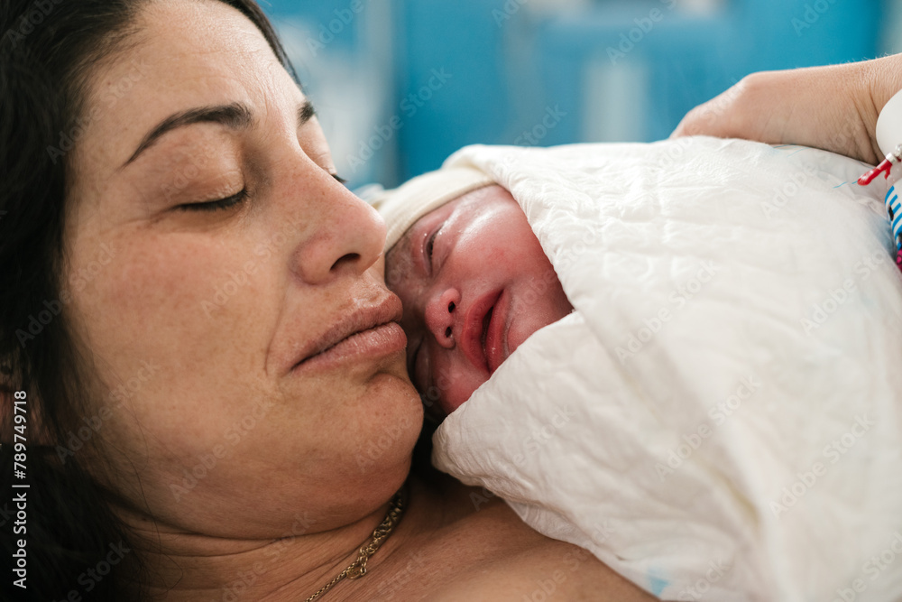 Calm mother with adorable newborn baby resting in hospital