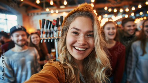 An enthusiastic woman taking a selfie with a group of friends at a beer festival, with taps and patrons softly out of focus behind her. Shallow depth of field, blurred background