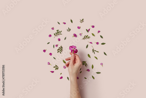 Woman's hand putting purple flower in center of floral round frame photo