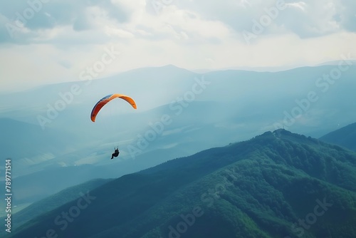 Paraglider flying over mountains in summer day .