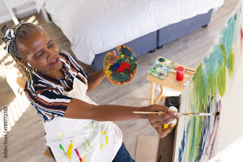 A senior African American woman is painting on canvas at home photo