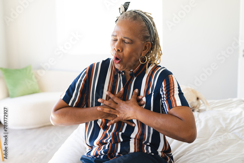 A senior African American woman with grey hair is having chest pains at home photo