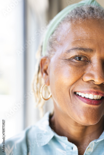 African American senior woman wearing hoop earrings is smiling at home, copy space photo