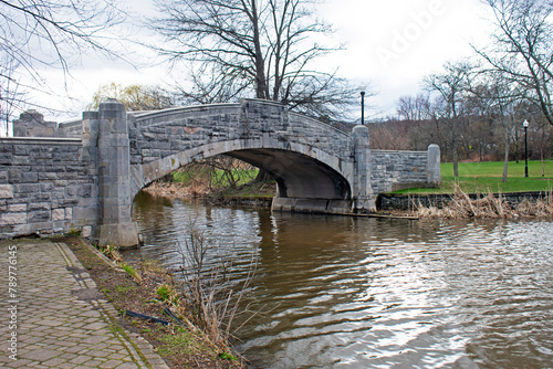 Cute stone bridge over Verona Lake in Verona Park, Verona, New Jersey, on an overcast day in early springtime -01