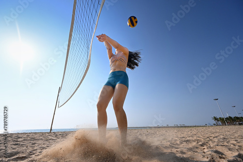 The moment of beach volleyball game, sportswoman break herself immediatly to hit the ball in front of the net  photo