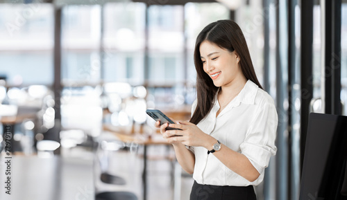 Free Download Young happy business woman, smiling beautiful professional lady worker looking at smartphone standing in office. - GFXLoad