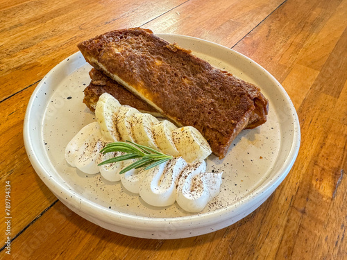 Delicious tiramisu french toast with fresh cream  and maple sirup. Tasty breakfast scene or dessert with toast, bananaand powdered sugar. photo