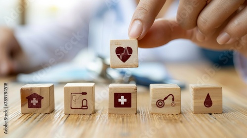 A hand placing a block with a heart icon on a table with other blocks with healthcare related icons. photo