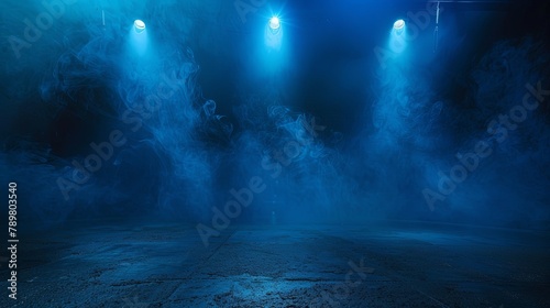 Blue spotlights illuminate an empty stage covered in smoke photo