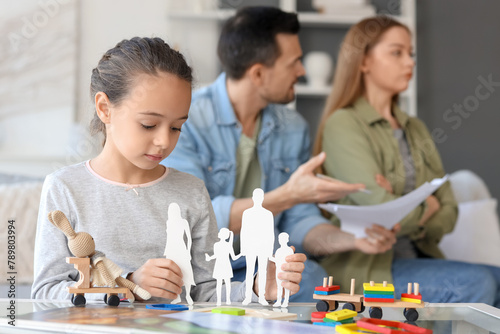 Sad little girl with family figure and her parents getting divorce at home