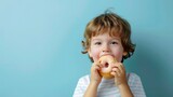 Cute little boy eating a donut on a blue background