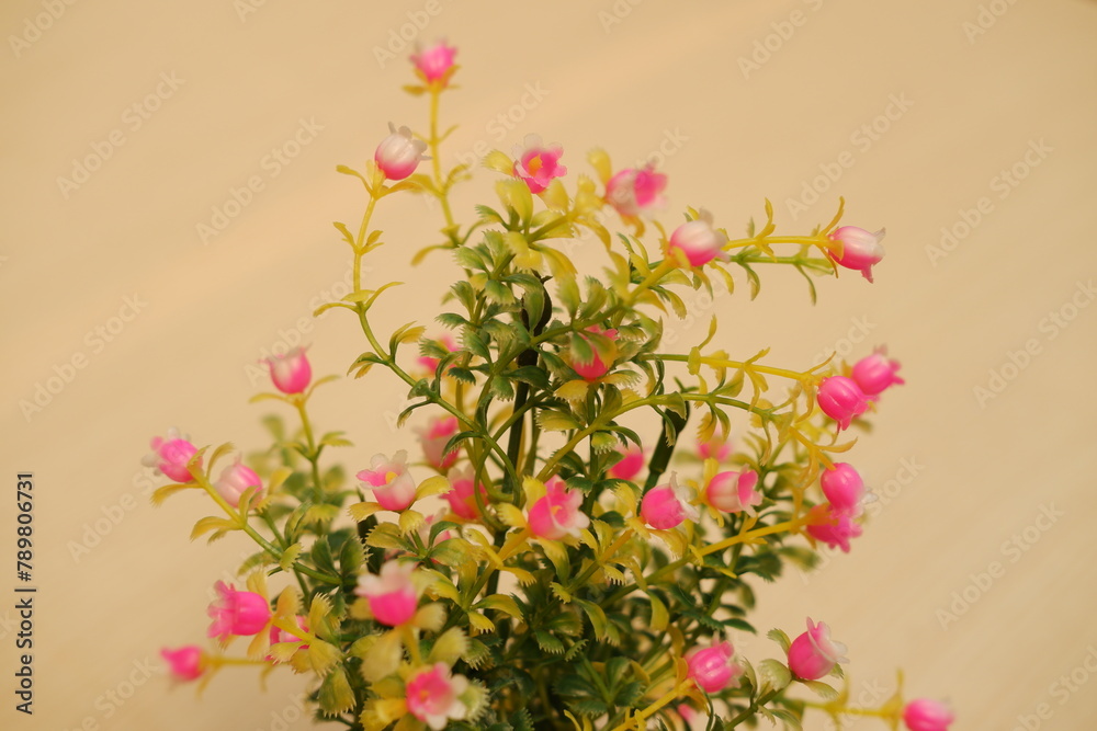 Small artificial flowers in vase on wooden table. Selective focus.