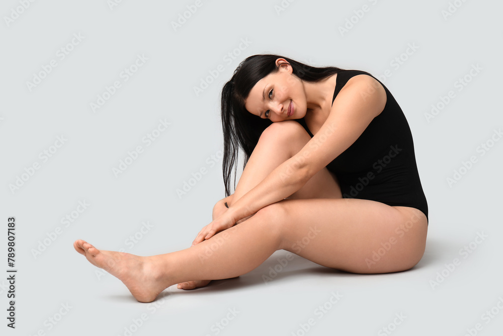 Body positive young woman sitting on light background