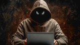   A person uses a laptop computer while wearing a hoodie with a creepy face design on its hood