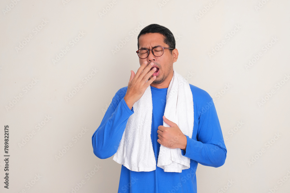 A man with bath towel around his neck yawning sleepy A man with bath towel around his neck yawning sleepy