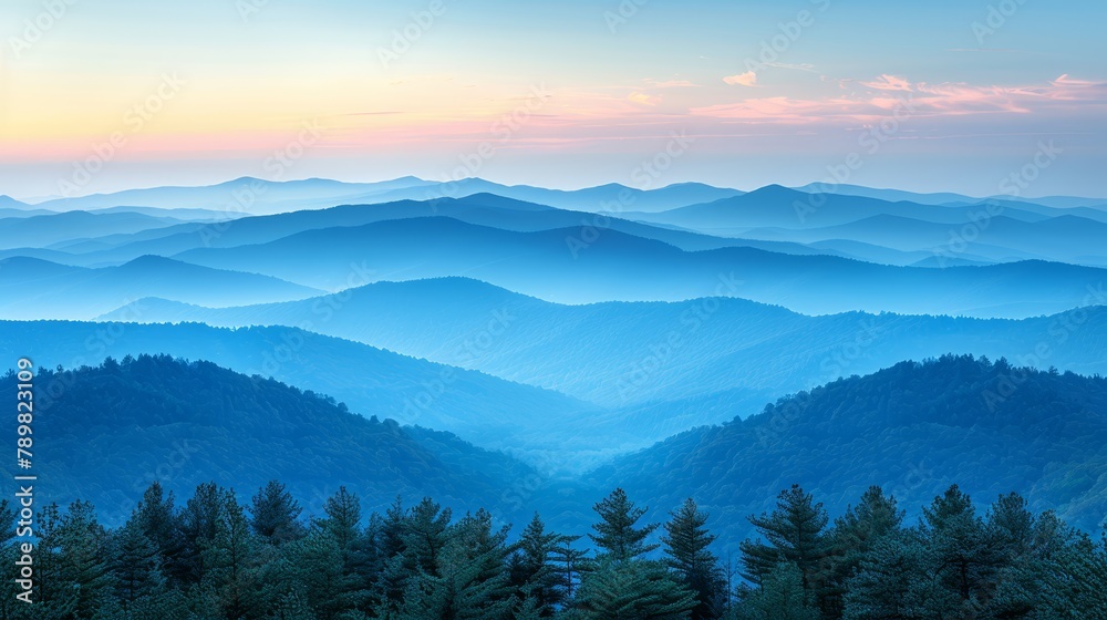   A mountain range view with trees in foreground and sun setting in the distance