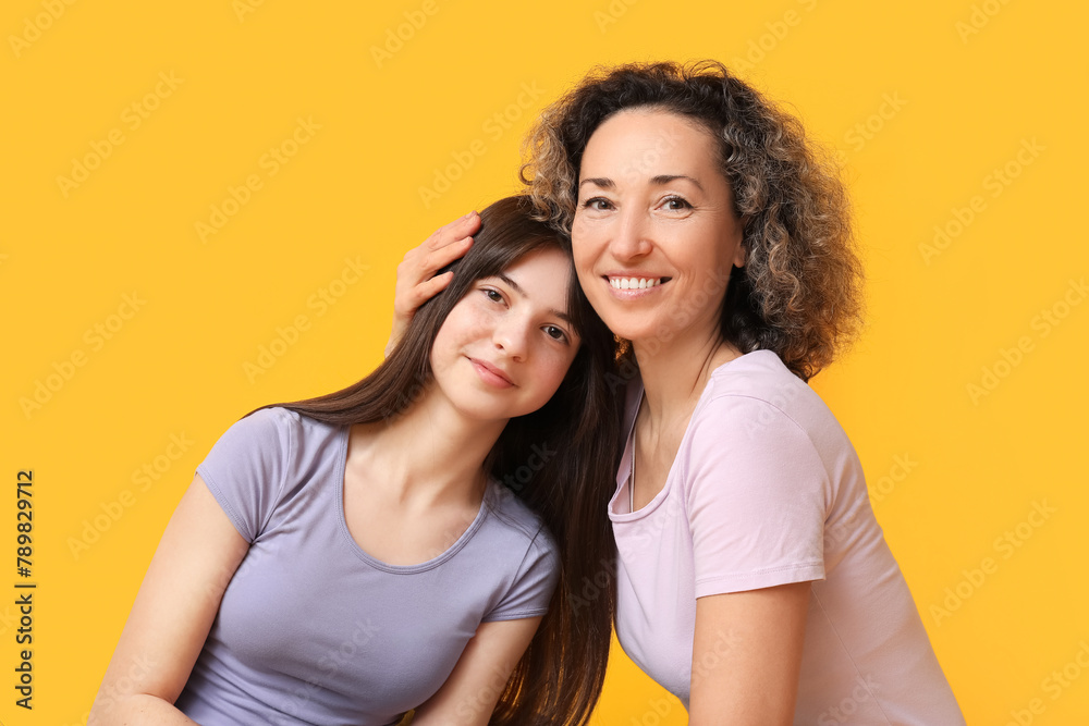 Beautiful mature woman with her teenage daughter on yellow background. Mother's day Beautiful mature woman with her teenage daughter on yellow background. Mother's day