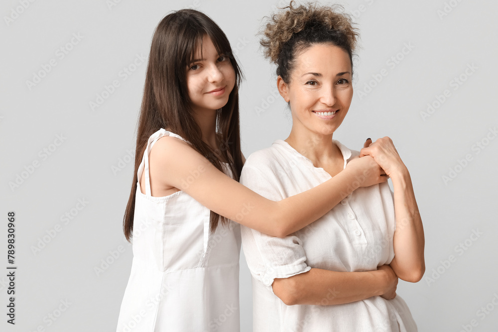 Beautiful mature woman with her teenage daughter hugging on grey background. Mother's day Beautiful mature woman with her teenage daughter hugging on grey background. Mother's day
