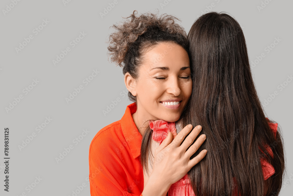 Beautiful mature woman hugging her teenage daughter on grey background. Mother's day Beautiful mature woman hugging her teenage daughter on grey background. Mother's day