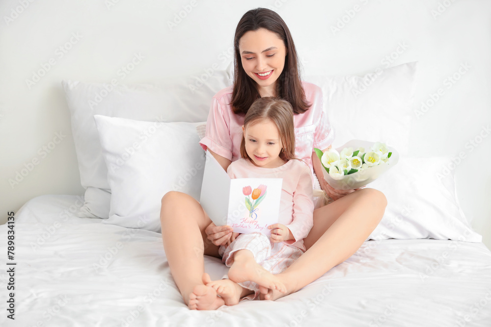 Happy mother with gifts and her cute little daughter sitting in bedroom Happy mother with gifts and her cute little daughter sitting in bedroom