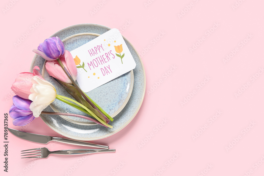 Fototapeta premium Table setting with greeting card for Mother's day and tulips on pink background