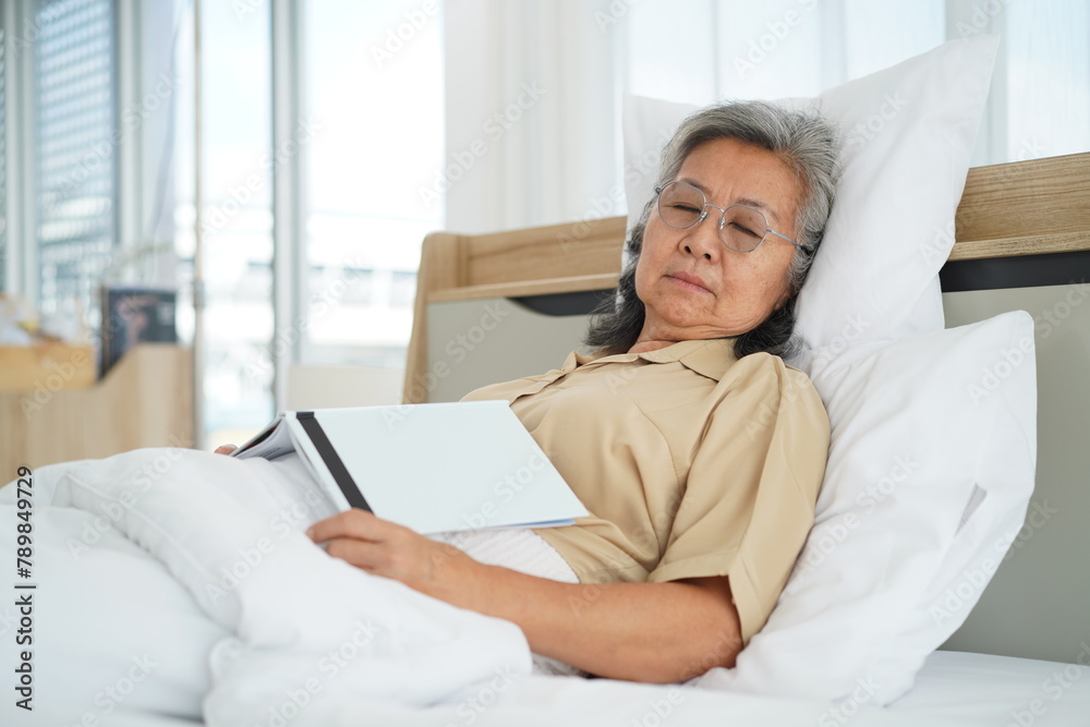 Happily elderly woman lying on bed and reading book Happily elderly woman lying on bed and reading book