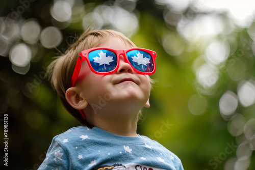 Joyful child in Canada Day celebration sunglasses with maple leaf design.