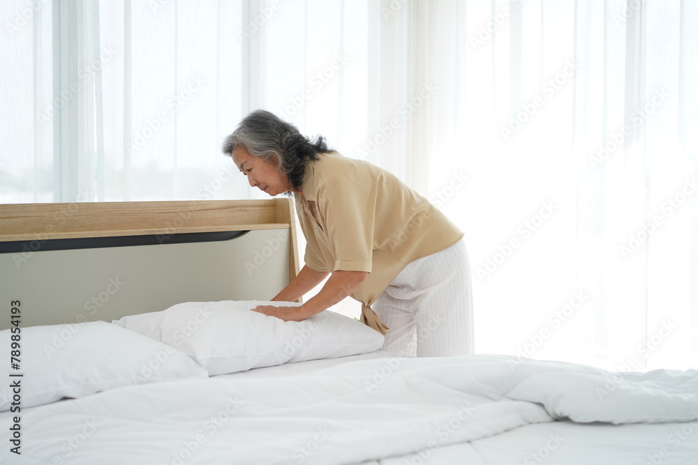 Asian elderly woman was cleaning the dusty bed in bedroom Asian elderly woman was cleaning the dusty bed in bedroom