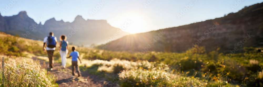 Panoramic image of a family walking in the mountains at sunset