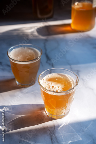 Two glass of homemade Kombucha on the marble table, fermented tea beverages in the sunlight.
