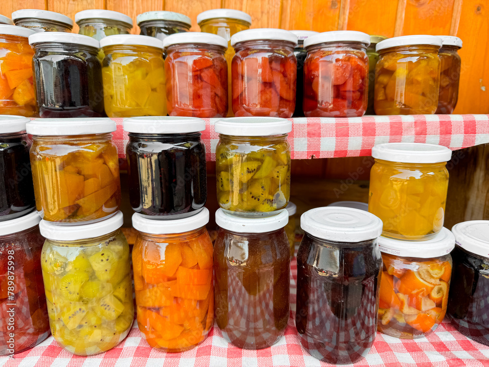 Assortment of homemade preserves in glass jars with checkered cloth, various pickled fruits and vegetables, colorful display, canned goods collection, close up with selective focus. Assortment of homemade preserves in glass jars with checkered cloth, various pickled fruits and vegetables, colorful display, canned goods collection, close up with selective focus.