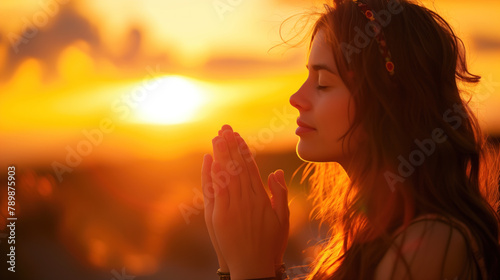 Young woman in serene prayer at sunset surrounded by nature.