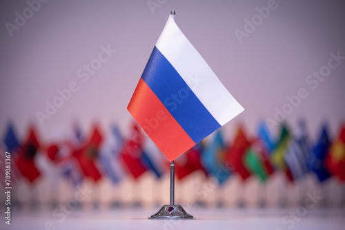 Fototapeta Naklejka Na Ścianę i Meble -  A small Russian flag flies among a row of other flags under an electric blue sky