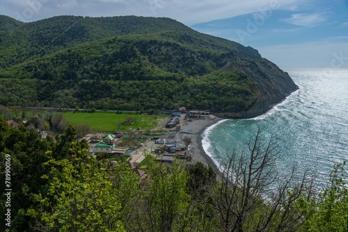 Black Sea, beach and steep shore near the green wooded mountains of the Western Caucasus near the village of Durso (South of Russia) on a sunny spring day
