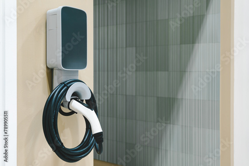 Electric car small home wall charger with cable. Plug for vehicle with electric engine. EV charger. Clean energy. Charging point at car parking lot. Future transport technology. photo