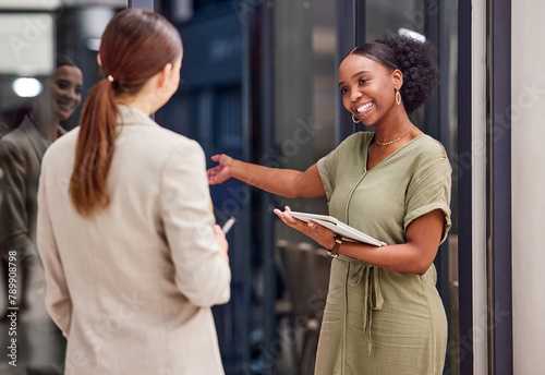 Smile, business women and direction to meeting in office on digital tablet at diverse startup company. Welcome, staff team and happy professional secretary or creative assistant greeting to show way