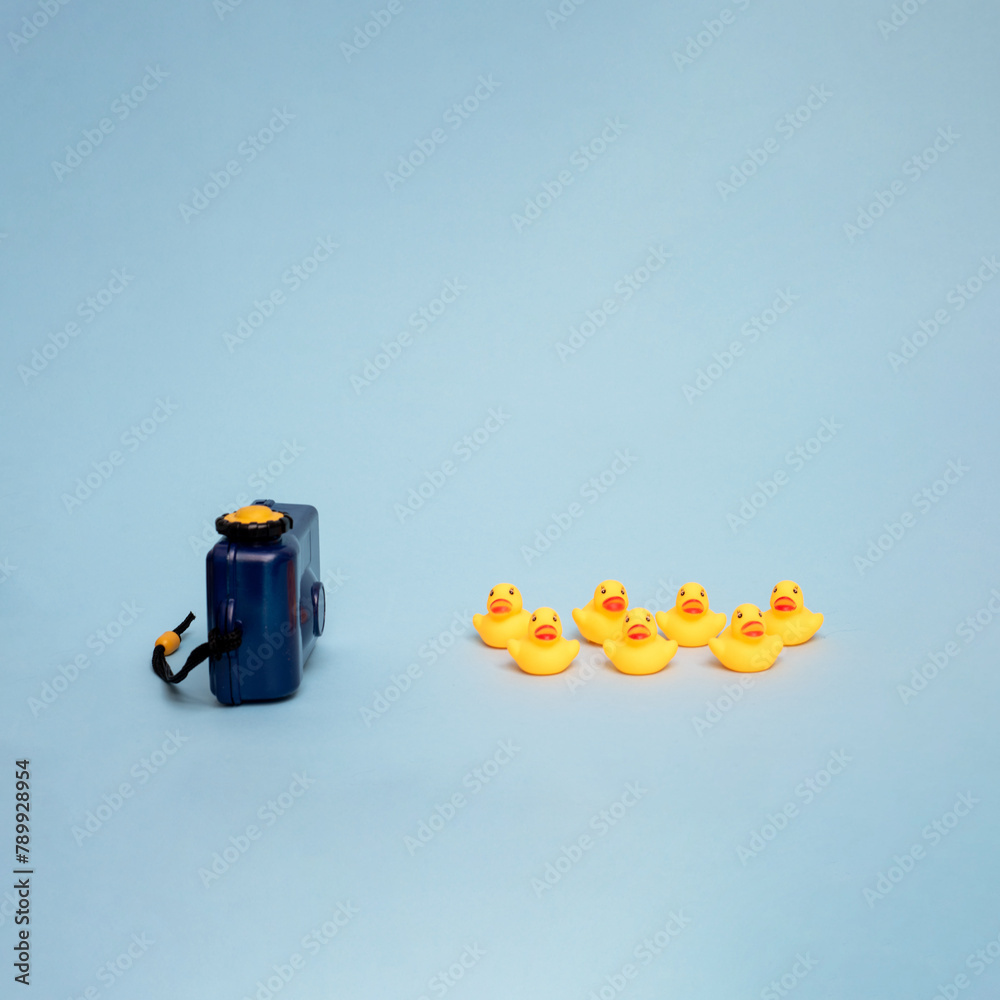 Creative summer objects concept. Toy camera and rubber ducks on a blue background. 