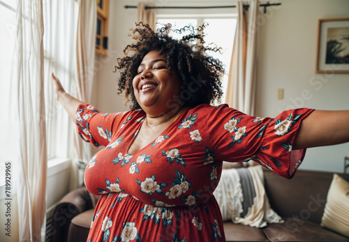 happy plus size africane american woman dancing and laughing in living room at home photo