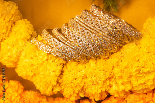 stone studded intricate bangles spread on yellow marigold flowers