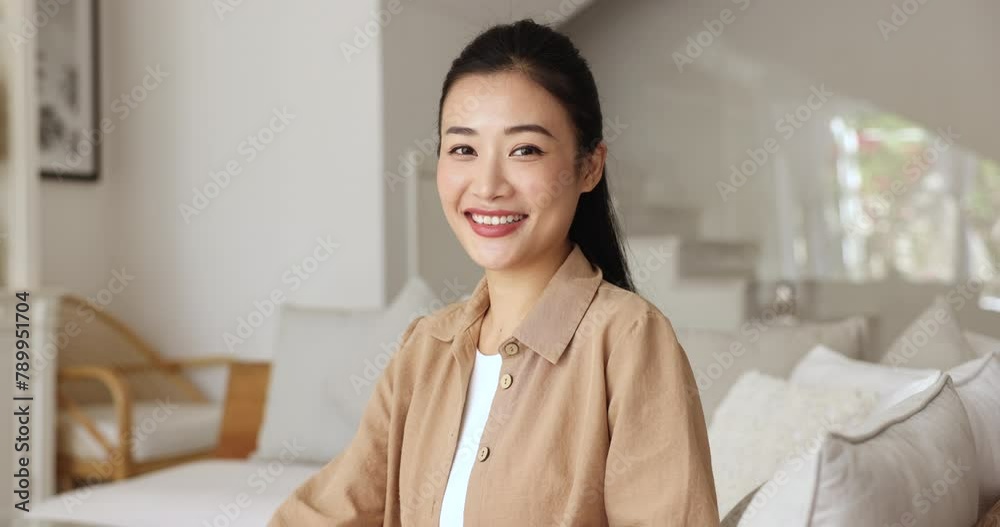 Portrait of happy and satisfied good-looking young Chinese lady posing for camera seated on sofa in fashionable living room in her own or rented apartment, smile, enjoy carefree leisure alone at home Portrait of happy and satisfied good-looking young Chinese lady posing for camera seated on sofa in fashionable living room in her own or rented apartment, smile, enjoy carefree leisure alone at home