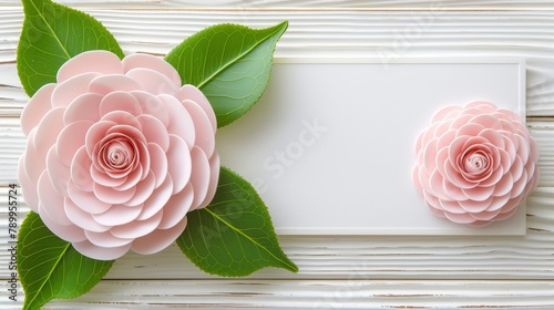   Two pink paper flowers with green leaves against a pristine white backdrop – ideal for affixing cards or name tags photo