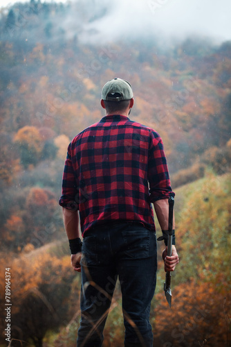 Epic Portrait of Strong Man Standing in Rainy foggy Autumn Forest 