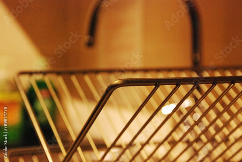 closeup of a dich rack in a modern kitchen with warm light and a faucet in the background photo