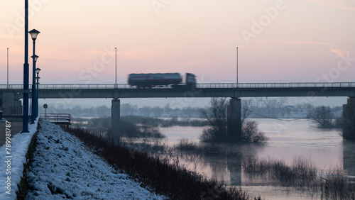 Truck driving across bridge during twilight, bridge across Sava river in Brod during winter photo