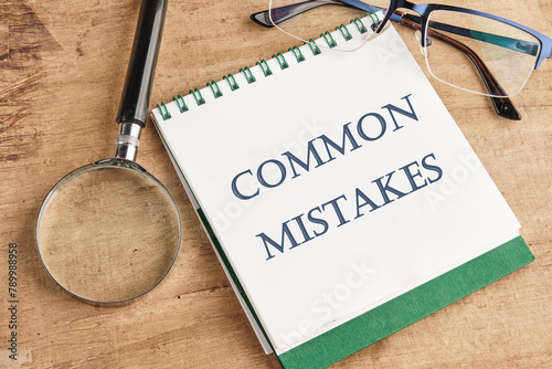 Common mistakes, text on a notebook with a magnifying glass and glasses on a vintage background