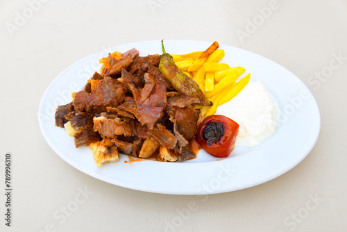 Turkish and Arabic Traditional Ramadan doner kebab with tasty tomato sauce and rice or turkish pilav in white plate on wood table background. ( Pilav ustu doner). Ekmek arasi doner, doner durum.  photo