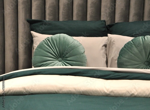 Modern bedroom interior at morning time with design furnishing and rounded pillows.The best cushion arrangement in grey and green.