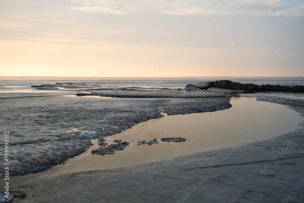 A vast body of water bordered by rocky shores and sandy beaches