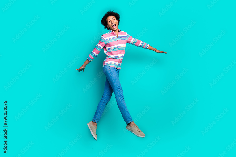 Photo of cheerful carefree man wear trendy striped clothes enjoy walk isolated on cyan color background