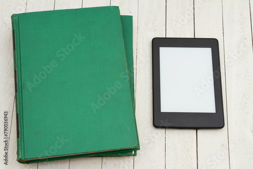 Retro old green book on a desk with an ereader
